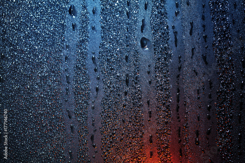 Raindrops on sweaty window with red tint photo