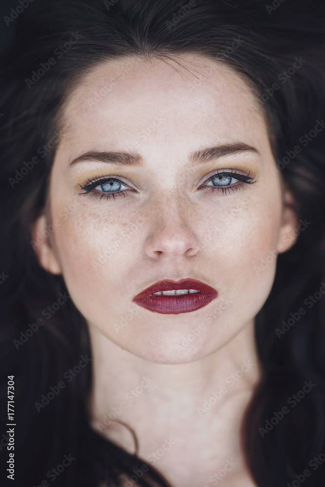 Portrait of a beautiful young woman with freckles and blue eyes