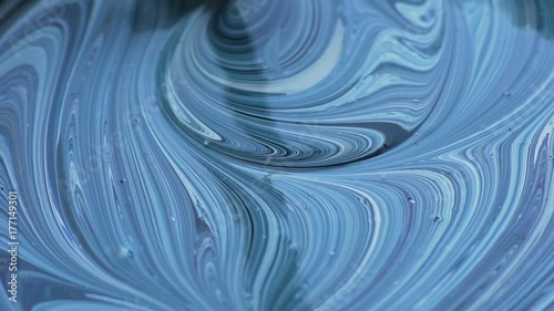 Inspired artist stirring paint mixture, leaving colorful patterns on surface