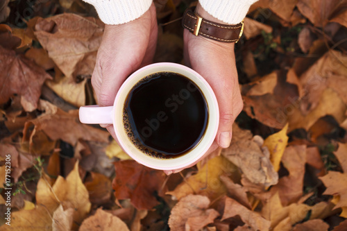 Сup of black coffee on a background of autumn foliage