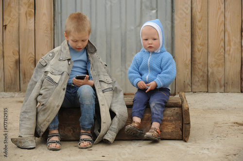 Two young guy plays with a phone and a prize for races on a rural farmstead in a hot summer
