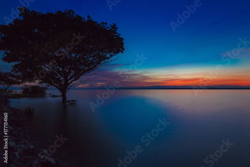 Sunset with tree reflection in a lake.