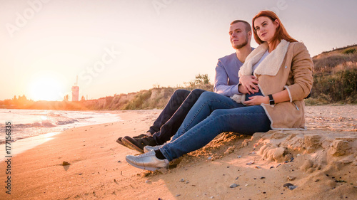 Couple sitting on the beach in autumn © Nik Viatkin