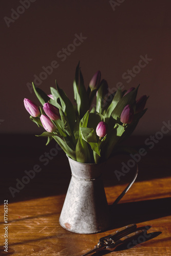 Lilac tulips in a galvanised jug on a sunlit table
