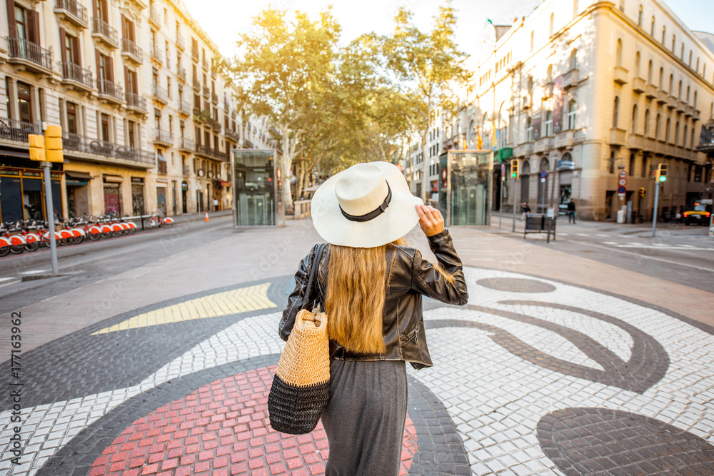 Fototapeta premium Młodej kobiety turystyczny odprowadzenie z powrotem na środkowej ulicie z sławnymi kolorowymi płytkami w Barcelona mieście