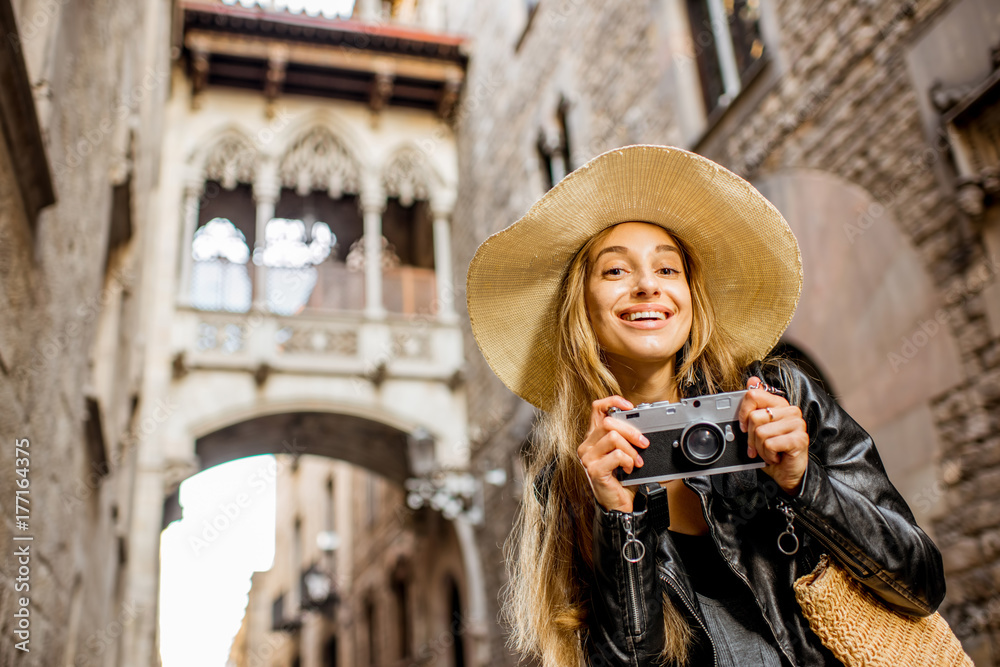Young woman tourist in hat standing with photo camera in front of the famous bridge of sighs in Barcelona old town Young woman tourist in hat standing with photo camera in front of the famous bridge of sighs in Barcelona old town