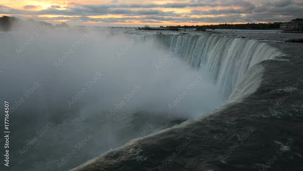 Dark view of Niagara Falls water in opposite to pink clouds of very early sunrise Dark view of Niagara Falls water in opposite to pink clouds of very early sunrise