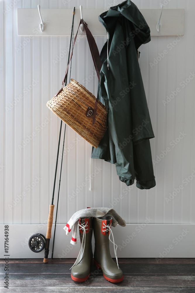 Raincoat, basket and fishing pole hanging on hooks Stock Photo