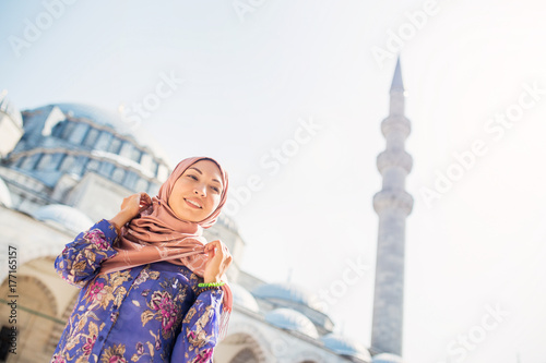 Happy woman in scarf with a backpack on the background of a mosque in Turkey © EdNurg