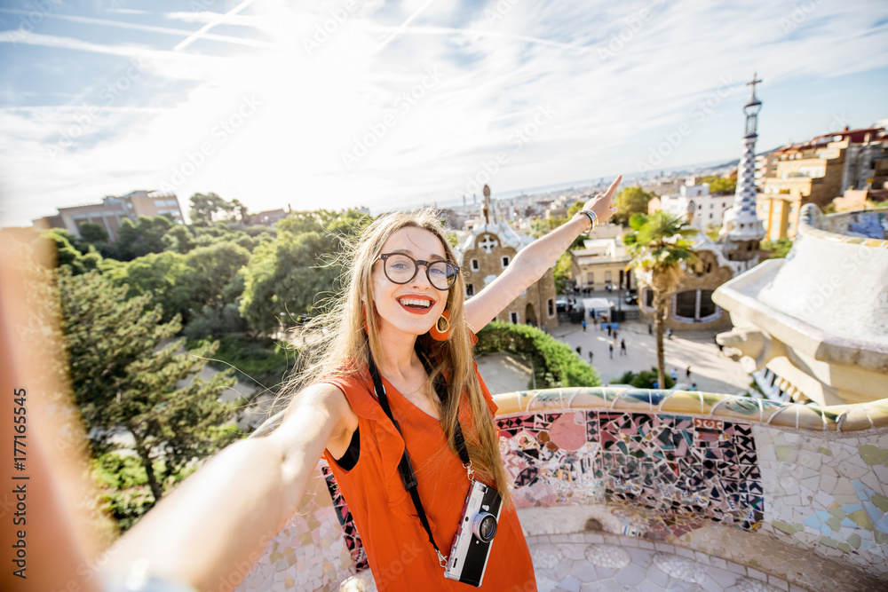Naklejka premium Woman tourist in red dress having fun visiting famous Guell park in Barcelona