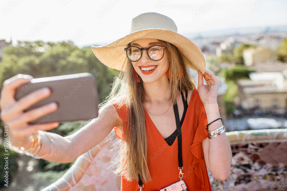 Fototapeta premium Portrait of a young woman tourist in red dress having fun visiting famous Guell park in Barcelona