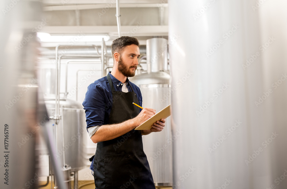 man with clipboard at craft brewery or beer plant