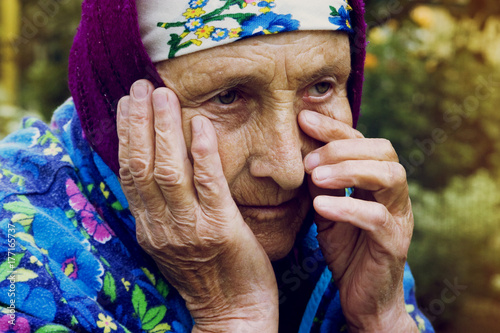 An old grandmother wipes a tear from her eyes