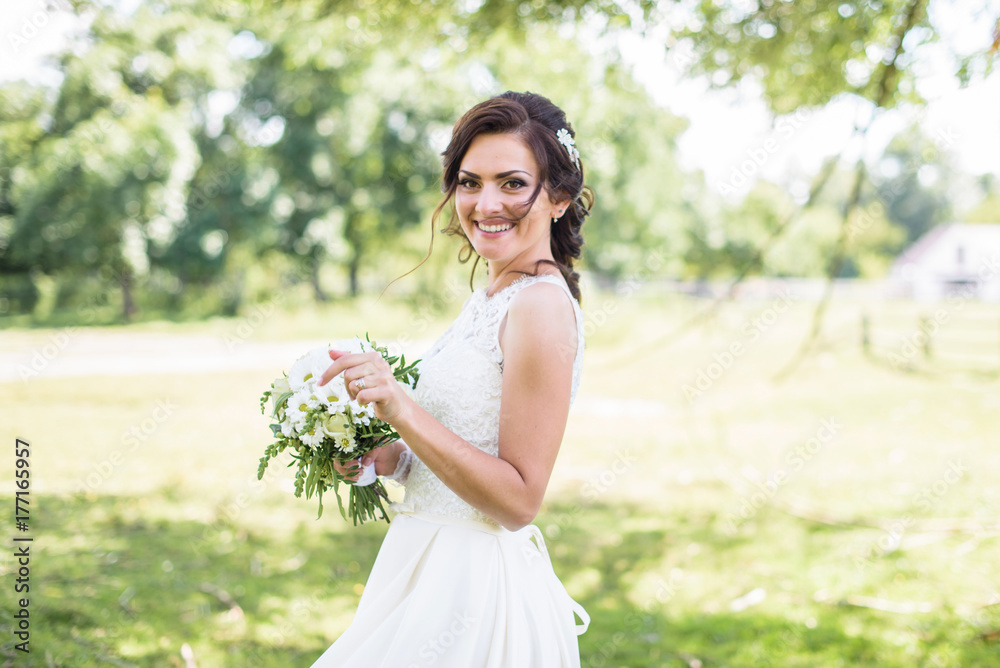 Beautiful bride in wedding dress outdoor in a field at sunset