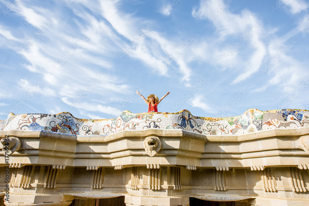 Fototapeta premium View on the beautiful terrace decorated with mosaic with happy woman tourist in Guell park in Barcelona. Wide angle view with copy space