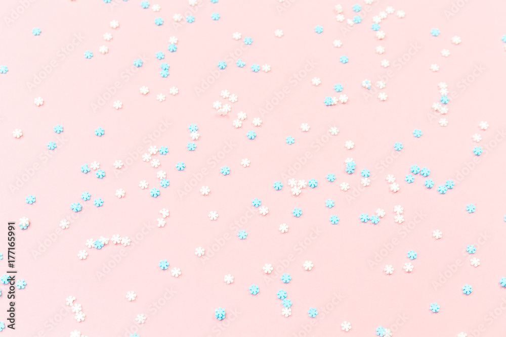 White and blue snowflakes sprinkles on pink. Festive holiday background. Celebration concept
