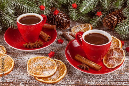 Christmas banner with green tree, cones, red cups with hot chocolate, orange and cinnamon on white wooden background. Empty space for text.