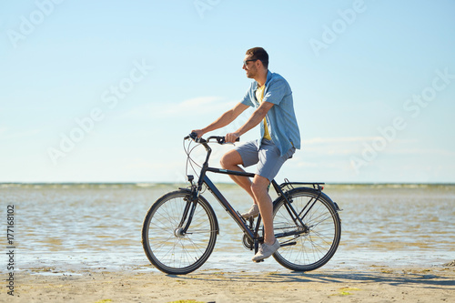happy man riding bicycle along summer beach