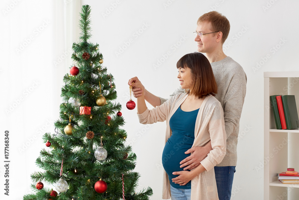 happy pregnant wife and husband at christmas tree happy pregnant wife and husband at christmas tree