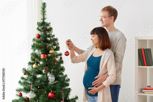 happy pregnant wife and husband at christmas tree