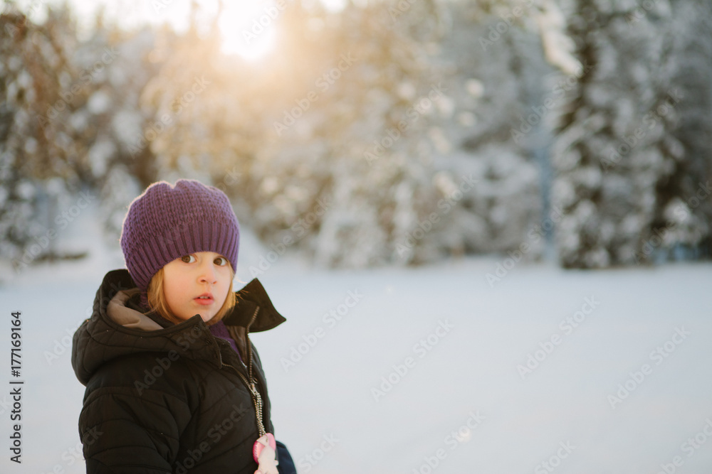 a girl looks at the camera as she skis through the woods in norway a girl looks at the camera as she skis through the woods in norway