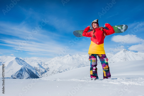 beautiful girl is holding a snowboard board on her shoulder. Smiling