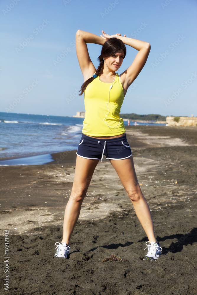Beautiful brunette stretching on beach after jogging