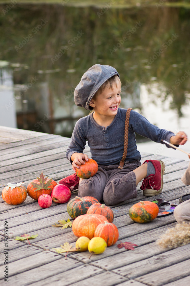 Fototapeta premium Laughing boy sitting with Halloween pumpkins