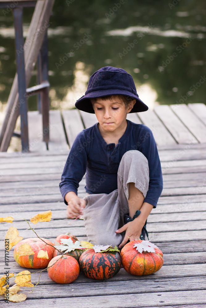 Fototapeta premium Smiling boy sitting with pumpkins