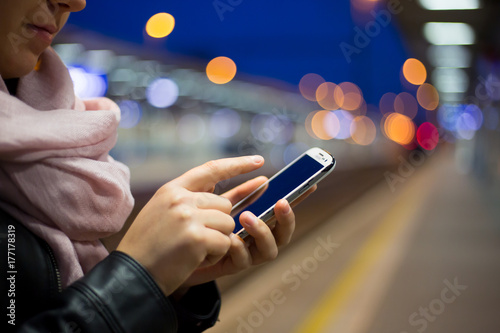 Young woman calling on a mobile at train station during early morning