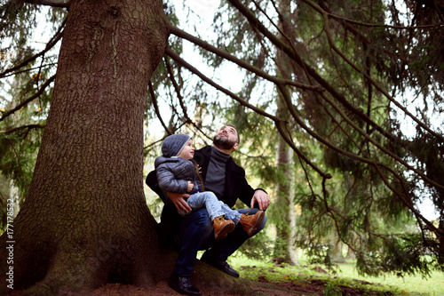 happy father and son under tree in forest