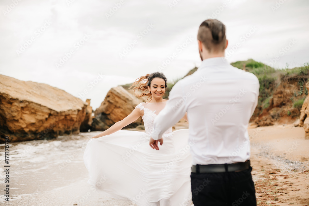 Obraz premium young couple groom with the bride on a sandy beach