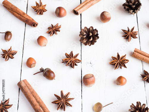 Cinnamon sticks spice star fir cones on white wooden background Flat lay