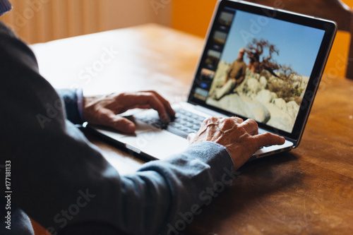 Senior man watching his vacation photos on his laptop photo