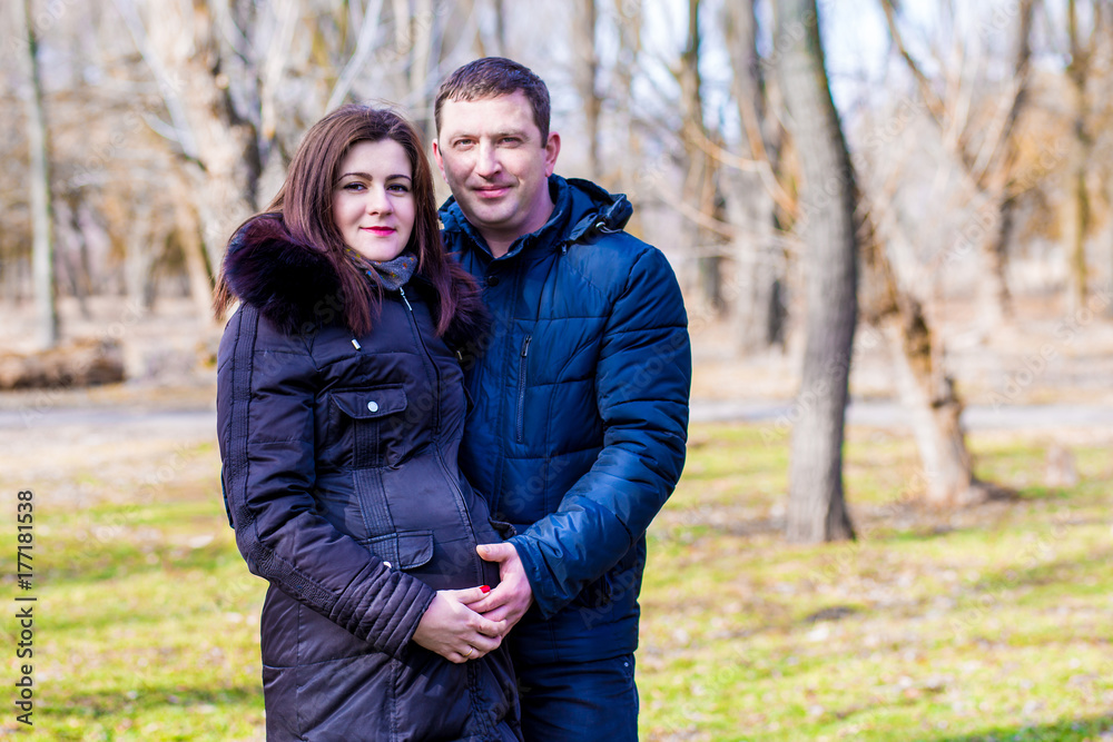 Beautiful pregnant woman and her handsome husband hugging the tummy Beautiful pregnant woman and her handsome husband hugging the tummy