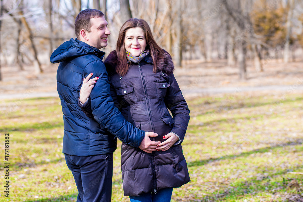Fototapeta premium Beautiful pregnant woman and her handsome husband hugging the tummy
