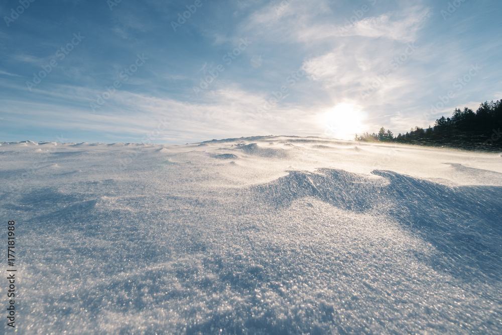 Schneebedeckter Hügel bei starkem Wind der die Flocken über den Hügel fegt