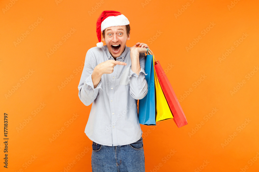 Positive happiness man looking at camera and toothy smile. Shocked man holding many bags and pointing fingers on them. Positive happiness man looking at camera and toothy smile. Shocked man holding many bags and pointing fingers on them.
