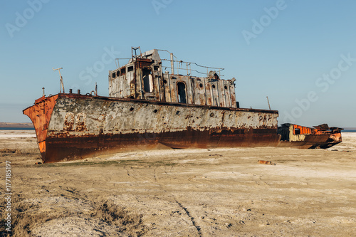 Aral sea disaster. Abandoned rusty fishing boat at the desert on the place of former Aral sea photo