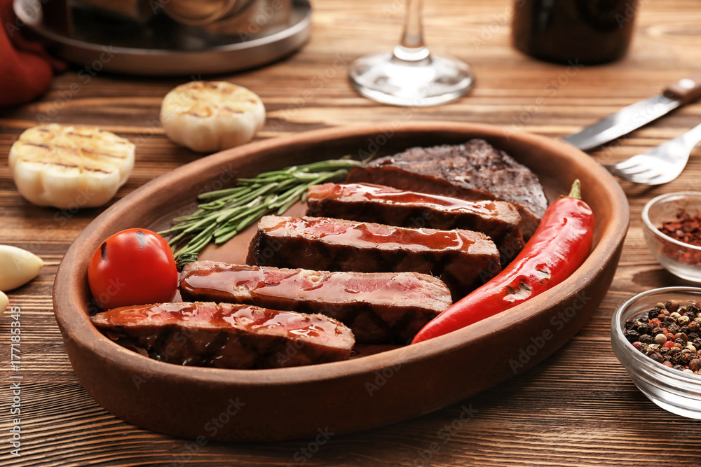 Plate with delicious grilled steak on wooden table