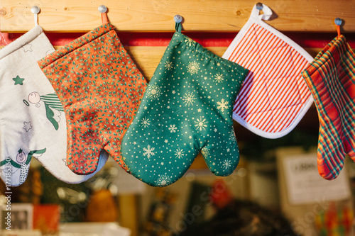 Christmas mittens potholders hang in kitchen against the background of blurry kitchen appliances. photo