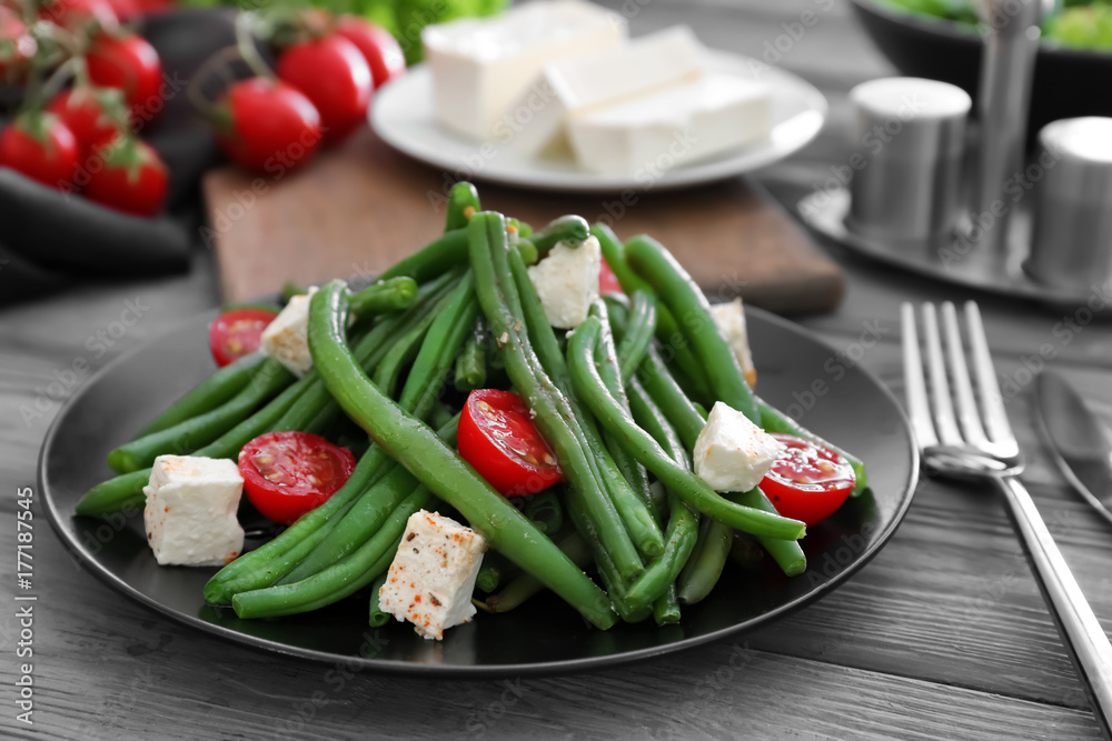 Plate with delicious green beans salad on wooden table