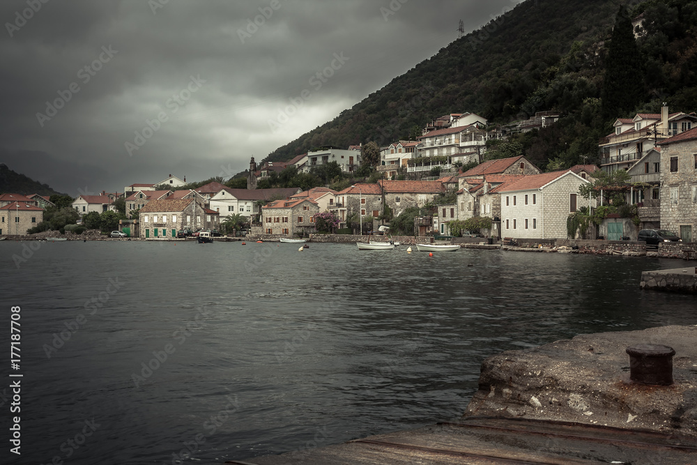 Promenade in old medieval port town Lapetane in rainy overcast day in Montenegro 