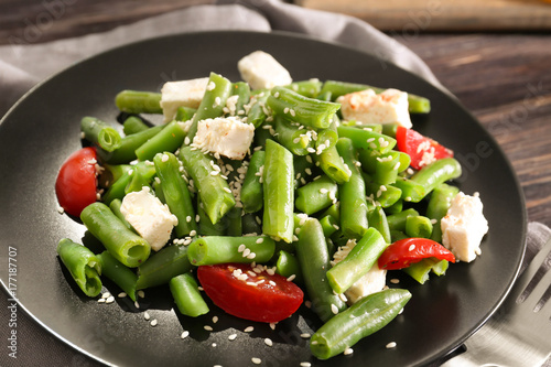 Plate with delicious green beans salad on wooden table, closeup