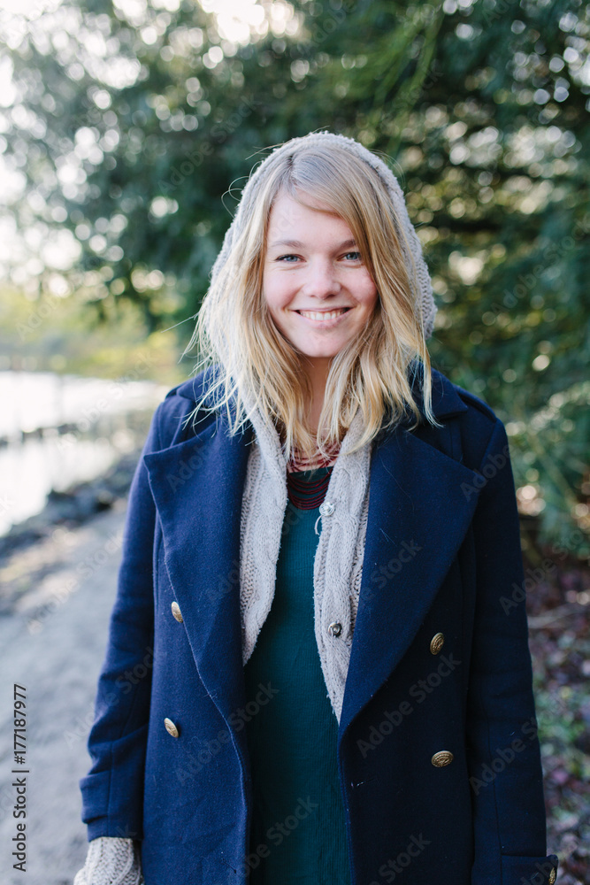 A young white woman laughing and looking at the camera while standing a forest path A young white woman laughing and looking at the camera while standing a forest path