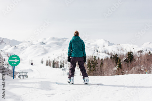 Female snowboarder in front of a beginner ski slope.