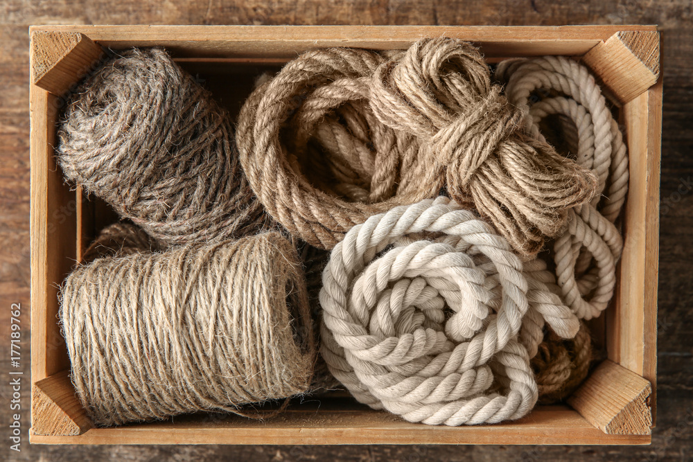 Hemp ropes in crate on wooden background
