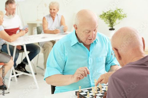 Elderly men playing chess a...