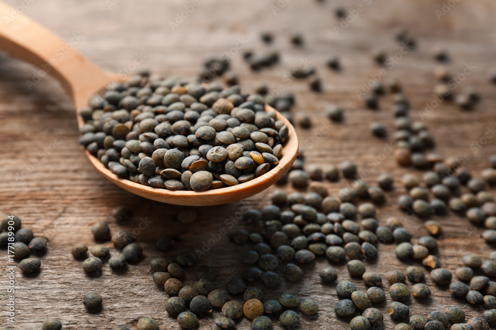 Spoon with green lentils on wooden table Spoon with green lentils on wooden table
