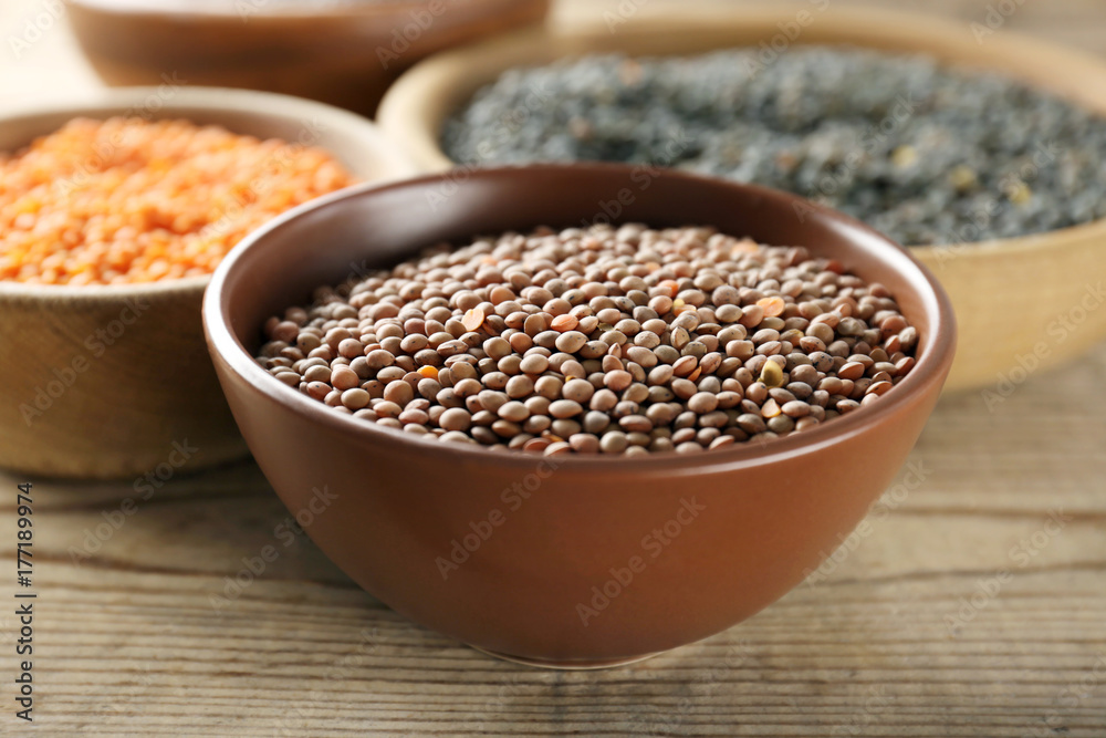 Bowl with brown lentils on wooden table Bowl with brown lentils on wooden table